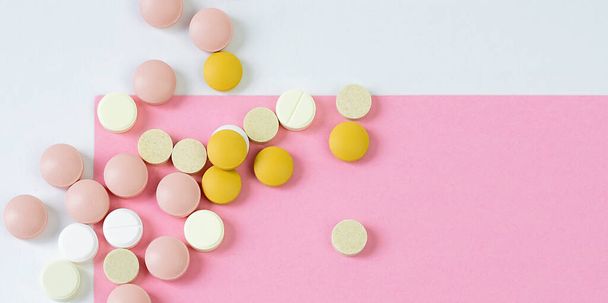 Stapel von Pillen bunt auf weißem - rosa Hintergrund - Foto, Bild