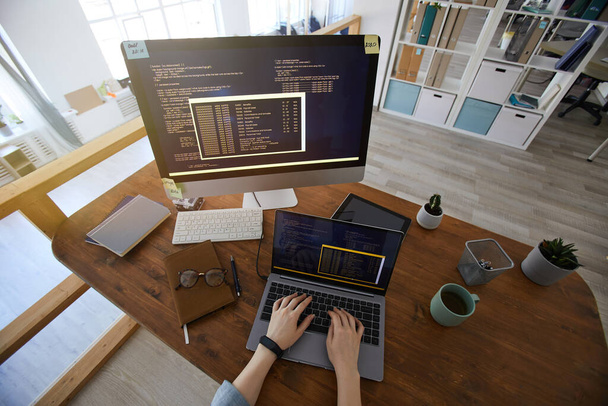 Широкий кут огляду над жіночими руками, що друкуються на клавіатурі під час кодування на робочому місці в сучасному офісному інтер'єрі, простір для копіювання
 - Фото, зображення