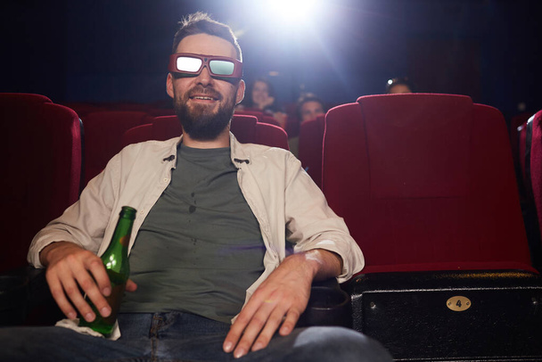 Vooraanzicht portret van lachende man met baard dragen stereo bril tijdens het kijken naar 3D-film in de bioscoop, kopieer ruimte - Foto, afbeelding