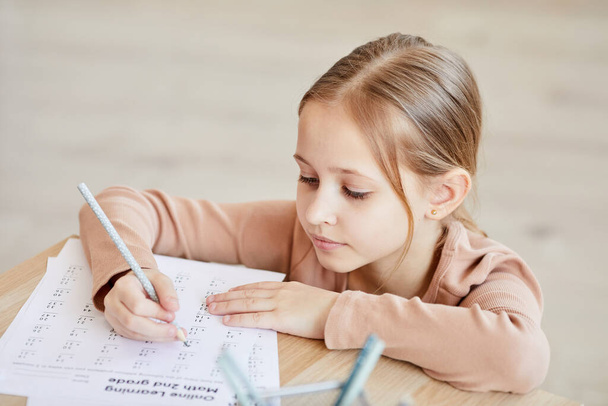 Duży kąt portret cute little girl robi test z matematyki dla szkoły online podczas nauki w domu, przestrzeń skopiować - Zdjęcie, obraz
