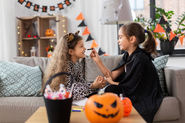 girls doing face painting on halloween at home - 写真・画像