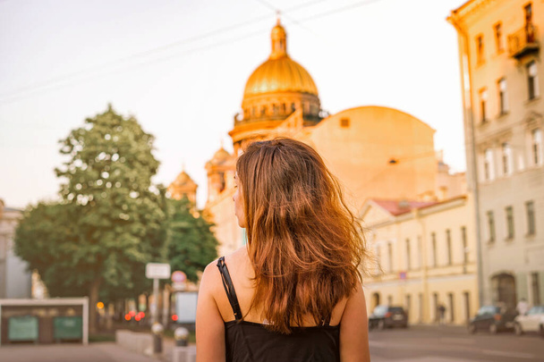 Foto trasera de una niña con el pelo largo sobre el fondo de la Catedral de San Isaac en San Petersburgo - Foto, imagen