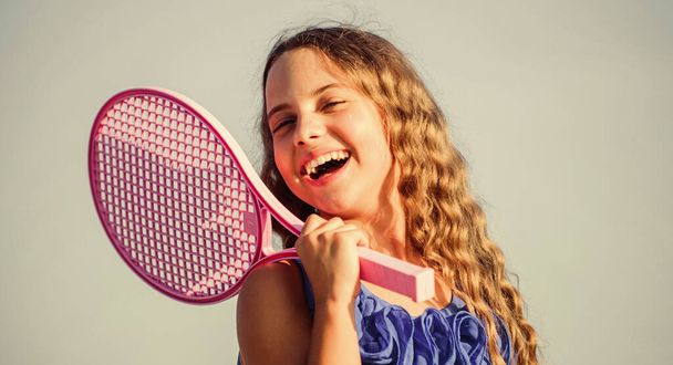 Summer leisure. Sport game. Playful cheerful kid. Happy childhood. Positive. Emotional baby. Active life. Child play tennis blue sky background. Sporty kid. Small girl with pink tennis racket - Photo, image