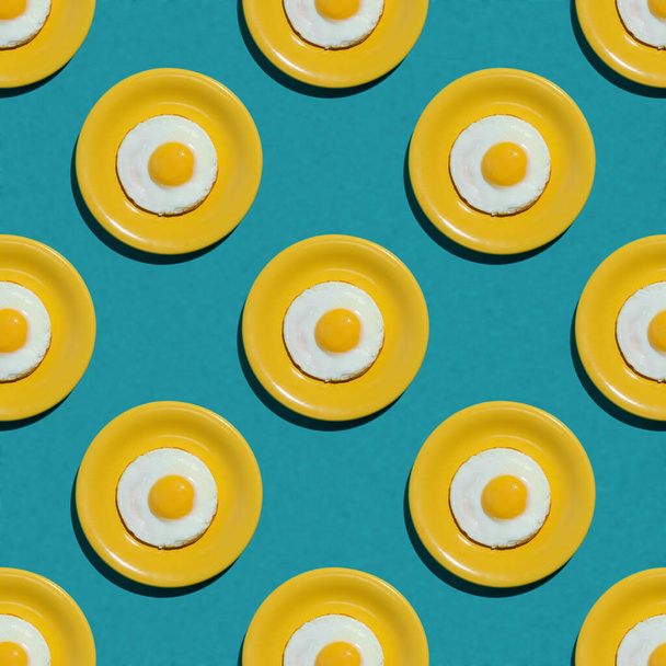 Fried egg on yellow plate seamless pattern on turquoise background. High resolution image. Flatly. Hard light. - 写真・画像