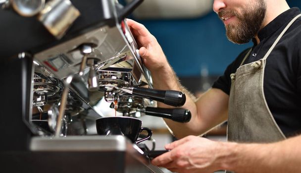A young barista guy makes coffee on a large professional coffee machine. - Foto, Bild