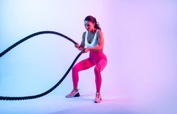 Fit woman training hard with ropes. Girl making exercizes in the gym. Concept about bodybuilding and lifestyle - Foto, Imagen