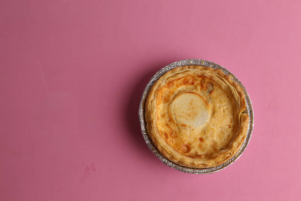 A top view of meat pie in foil cup on pink background - Фото, изображение