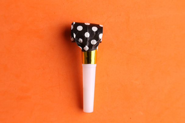 A closeup shot of a party noisemaker isolated on an orange background - Foto, Bild