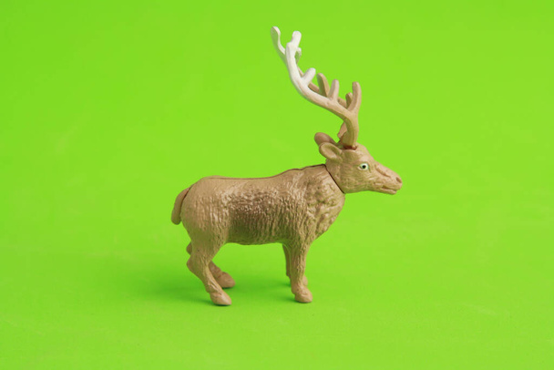 A closeup of a plastic reindeer toy on a green background - Fotoğraf, Görsel