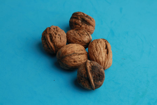 A high angle closeup shot of walnuts on a blue background - Fotoğraf, Görsel