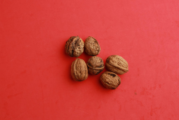 A top view of walnuts under the lights on a red surface - Foto, Bild