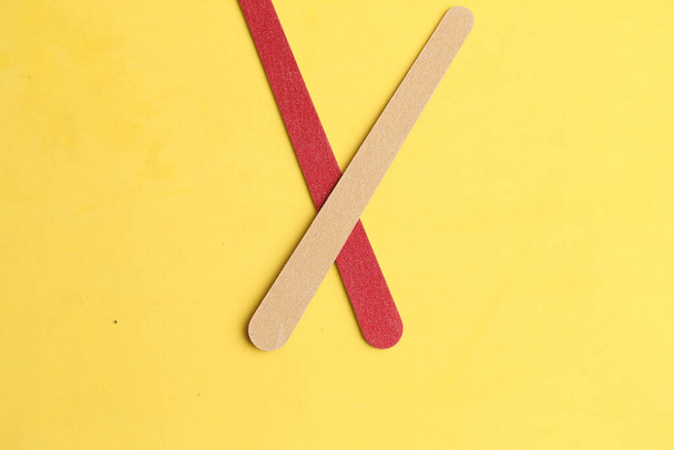 A closeup shot of the two wooden sticks isolated on yellow background - Zdjęcie, obraz