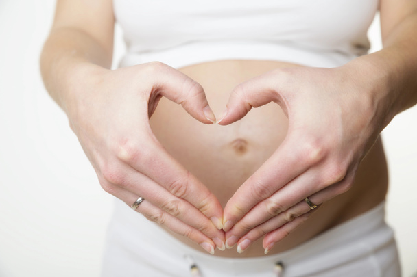 Femme enceinte faisant forme de coeur avec les mains
 - Photo, image