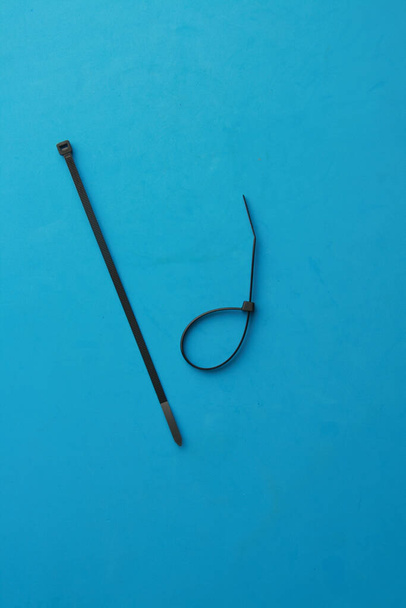 A closeup shot of the two plastic cable ties isolated on a blue background - Foto, Bild
