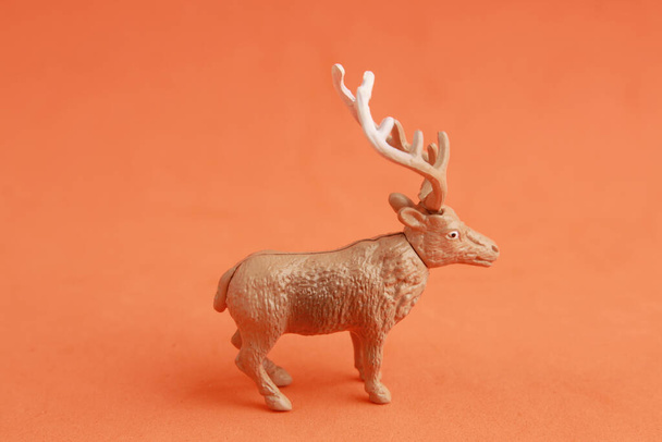 A closeup shot of a small toy deer isolated on an orange background - Valokuva, kuva