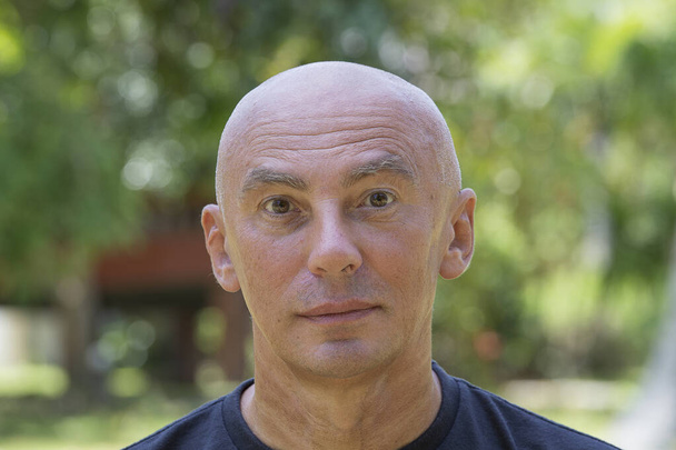 Close up portrait of a mature bald man against green nature background - Zdjęcie, obraz