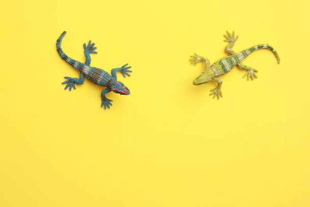 A closeup shot of lizard shaped rubber toys isolated on a yellow background - Фото, изображение