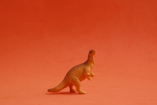 A small plastic dinosaur toy on a colored background - Fotoğraf, Görsel