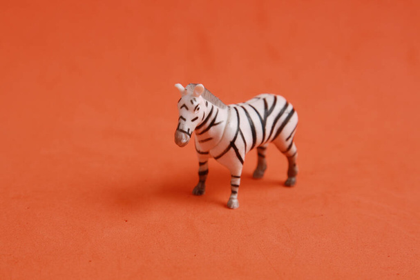 A closeup shot of zebra shaped plastic toy isolated on an orange background - Foto, afbeelding