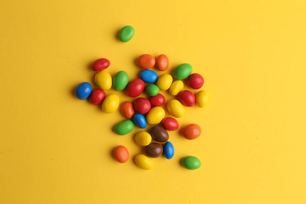The colorful chocolate balls with peanut on a yellow background - Φωτογραφία, εικόνα