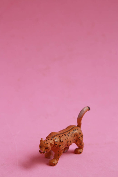 A vertical shot of a plastic leopard toy on a pink background - Foto, afbeelding