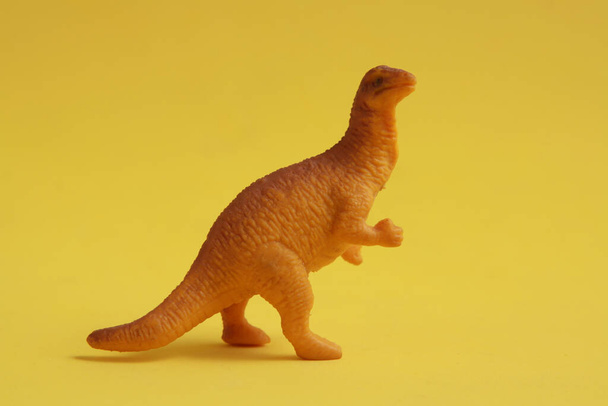 A closeup shot of a toy dinosaur miniature isolated on a yellow background - Fotó, kép