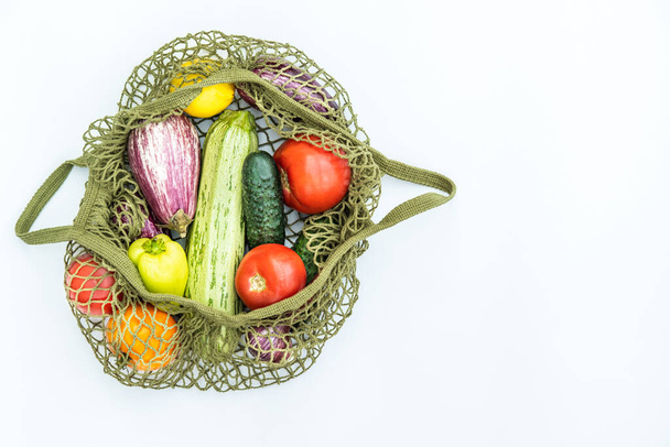 Bolsa de hilo verde con varias verduras frescas sobre fondo blanco. Concepto de cero residuos, verduras frescas en bolsas netas reutilizables. - Foto, imagen