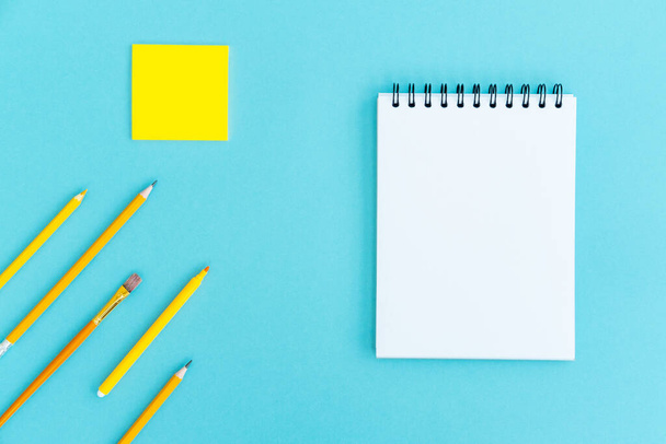 Open a blank notepad on the spiral and office and school supplies on blue background. Copy space, flat lay. Back to school concept. - Photo, Image