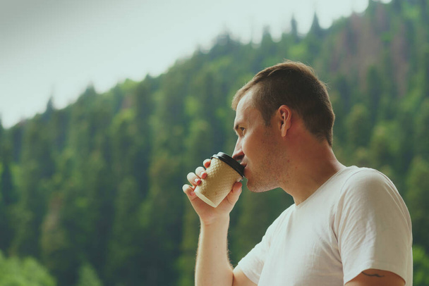 Adult male enjoying hot drink against mountain landscape. - Foto, imagen