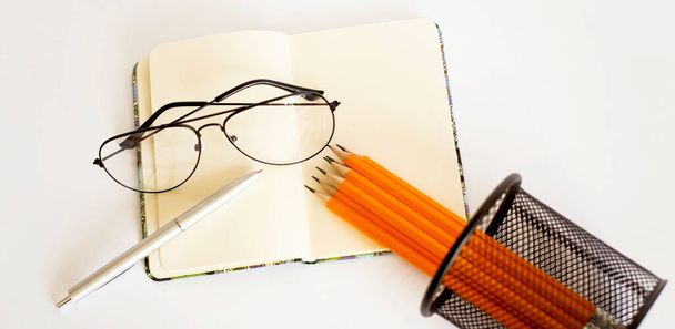 Bleistift auf geöffnetem Notizblock isoliert auf weißem Hintergrund mit Brille - Foto, Bild
