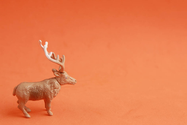 A closeup shot of a rubber toy deer isolated on an orange background - Foto, Imagen
