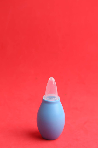 A closeup of a blue enema isolated on a red background - Foto, Imagen