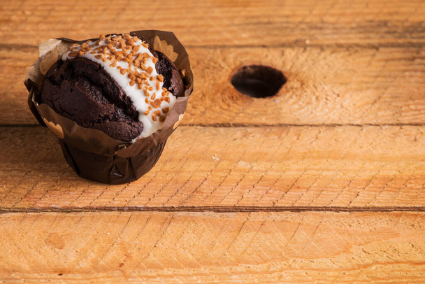 A closeup shot of a chocolate cupcake on a wooden surface - Foto, Imagem