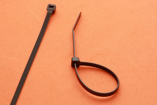 An isolated high angle top view closeup shot of a black plastic clamp on an orange table - Φωτογραφία, εικόνα