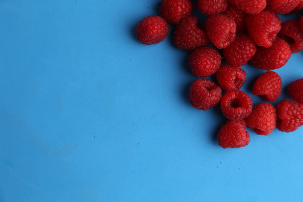 A closeup shot of raspberries isolated on a blue background - Photo, Image