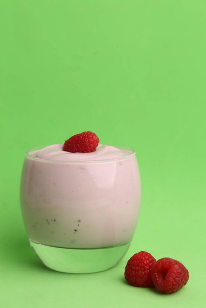 A vertical shot of raspberry yogurt on green background - Фото, зображення