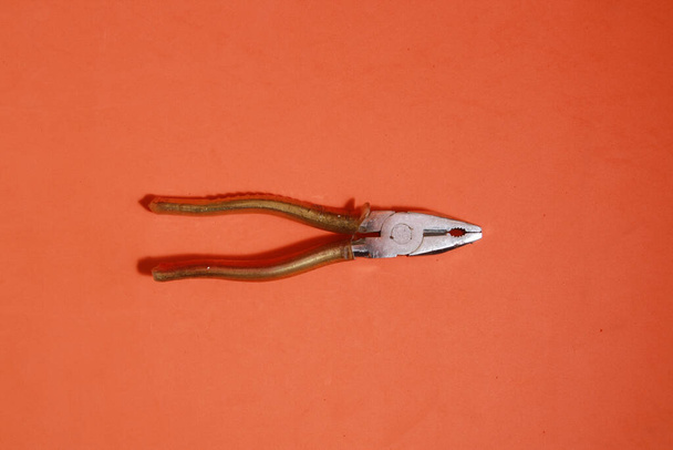 A closeup shot of pliers on an orange background - Foto, imagen