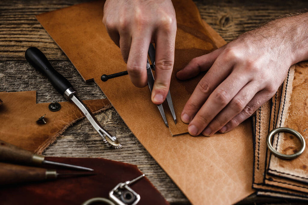 Close up of a shoemaker or artisan worker hands. Leather craft tools on old wood table. Leather craft workshop. - Fotoğraf, Görsel