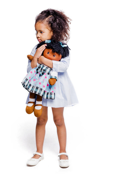 Muotokuva söpö pieni afrikkalainen amerikkalainen tyttö halaus nukke, eristetty valkoisella taustalla. Pystykuva - Valokuva, kuva