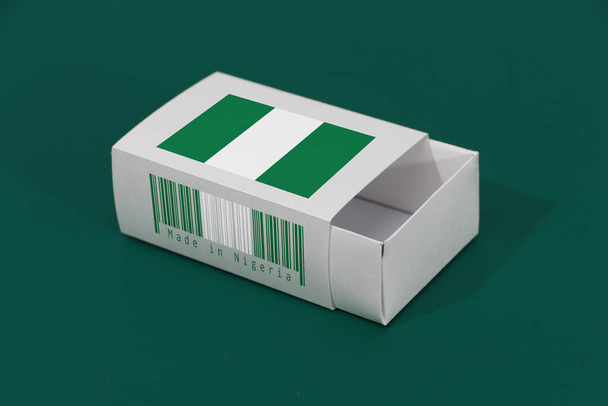 Nigeria flag on white box with barcode and the color of nation flag on green background, paper packaging for put match or products. The concept of export trading from Nigeria. - Photo, Image