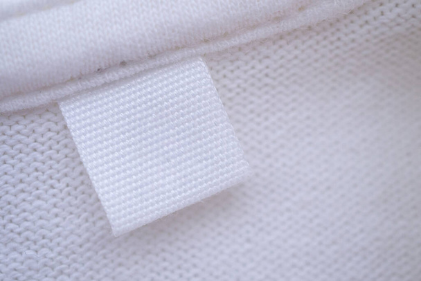 Blanco witte kleding label op nieuwe shirt achtergrond - Foto, afbeelding