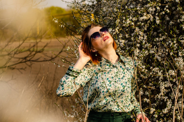 bela sorrindo jovem mulher posando em flores de pêssego ao ar livre - Foto, Imagem
