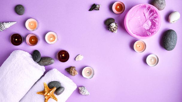 Spa still life treatment with candles, stones, sea shells starfish and towels on pink background, copy space for text, skincare products, natural cosmetics for home spa treatment - Photo, image