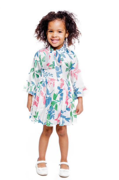 Portret van mooi klein Afrikaans Amerikaans meisje in witte bloemen jurk op witte achtergrond - Foto, afbeelding