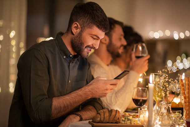 man with smartphone at dinner party with friends - Zdjęcie, obraz