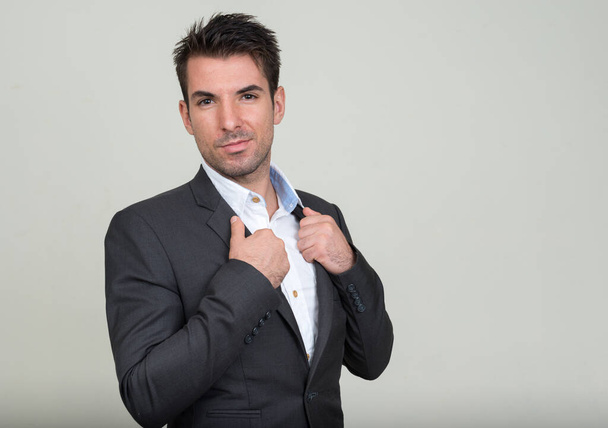 Студийный снимок молодого привлекательного латиноамериканского бизнесмена в иске на белом фоне - Фото, изображение