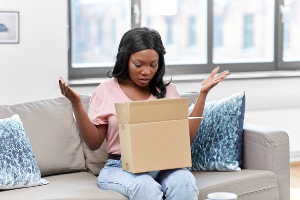 sad african american woman with parcel box at home - Foto, Imagem