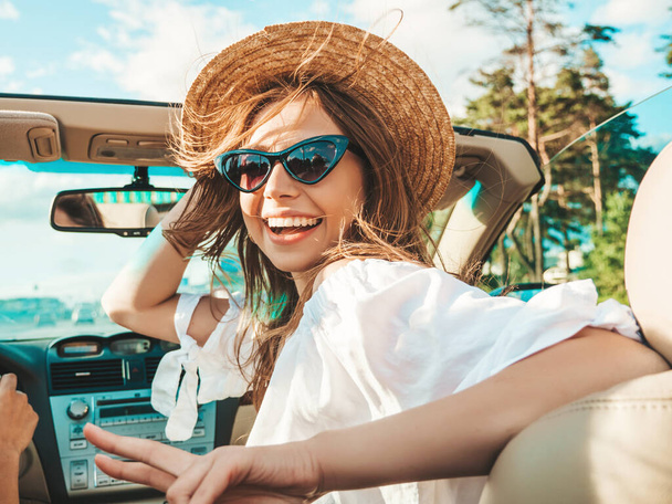Portrait of two young beautiful and smiling hipster girls in convertible car. Sexy carefree women driving cabriolet. Positive models riding and having fun in sunglasses - Photo, Image