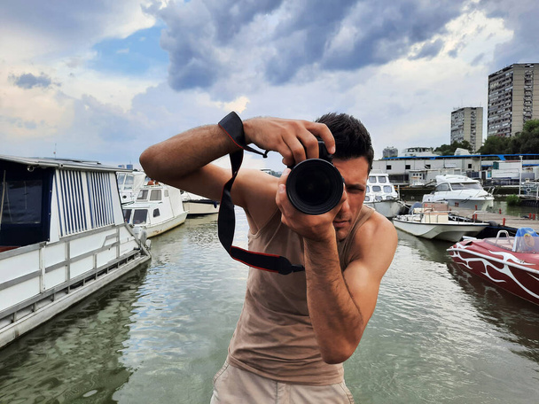 Photographer taking pictures at port with river, boats and yachts in the background - Foto, imagen