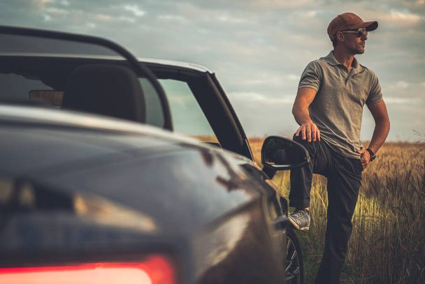 Életstílus és autóipari téma. Fehér férfi a 40-es éveiben, élvezi a vidéki utat egy kabrióban. Nyári időutazások. - Fotó, kép